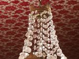 a chandelier hanging from a ceiling with a red and white wallpaper