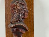 a statue of a man with a hat on top of a wooden plaque