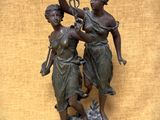 statue en bronze représentant deux femmes tenant un oiseau et une branche