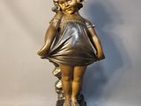statue d'une petite fille en robe, debout sur un socle