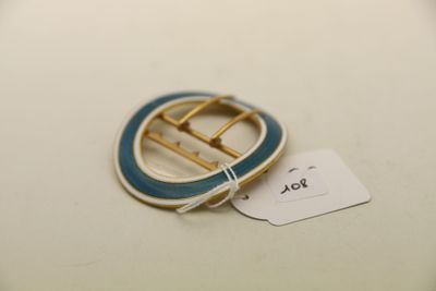 une photo d'une broche bleue et blanche à laquelle est accrochée une étiquette