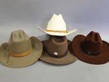 three hats are lined up on a table with a white background