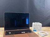 an apple laptop computer sitting on top of a wooden table next to a charger