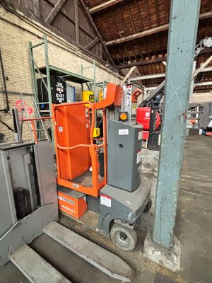 Une pince orange est entreposée dans un entrepôt avec d'autres équipements industriels