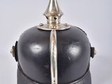 a small black object with a silver handle on a white surface