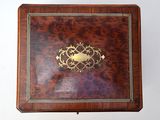 a small wooden box with a gold decoration on it