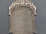 a silver metal purse with a chain around it