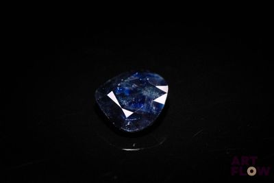 a close up of a blue sapphire stone on a black surface