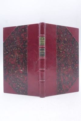 un vieux livre à la couverture rouge posé sur une surface blanche