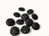 un tas de raisins secs noirs posé sur une surface blanche