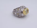 a close up of a yellow diamond ring on a white surface