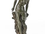 une statue antique en bronze représentant une femme tenant une fleur, posée sur un socle en marbre