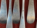 six silver spoons and a fork with a monogram on them