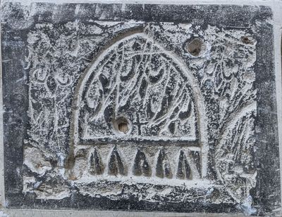 une image représentant une plaque en pierre sur laquelle figure un oiseau en cage