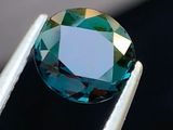 un gros plan d'un diamant bleu tenu par une pince