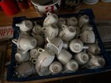a blue basket filled with cups and saucers on a table