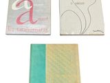 three books are sitting on a white surface one is green and the other is gold