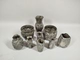 a group of silver vases sitting on a white surface