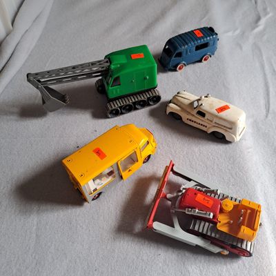 quatre petits véhicules jouets posés sur un lit