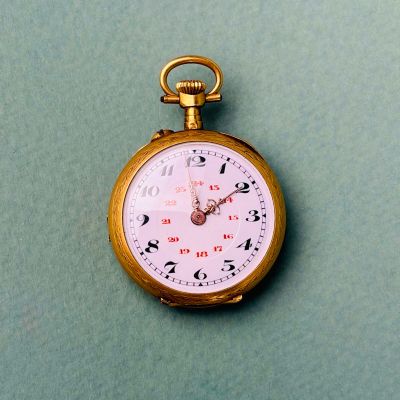 une montre de poche en or posée sur une surface verte
