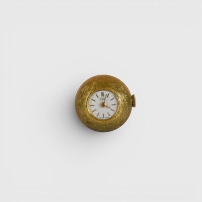 une vieille montre de poche en or avec un cadran blanc posée sur une surface blanche