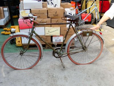 un homme debout à côté d'un vélo sur lequel sont posés des cartons