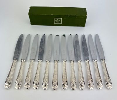 six silverplated knives and a box of knives on a table