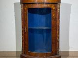 a corner cabinet with a blue glass door in the corner