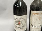 two bottles of red wine sitting next to each other on a white surface