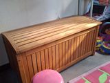 un banc en bois avec un pouf rose dans un coin de la pièce