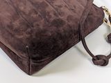 brown sued handbag on white background with strap and handle