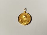 un gros plan d'une médaille d'or sur laquelle figure une image de Jésus