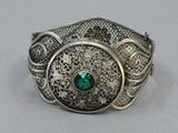 a close up of a silver ring with a green stone in it