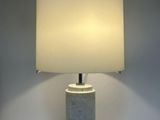 a white lamp sitting on top of a table next to a white wall
