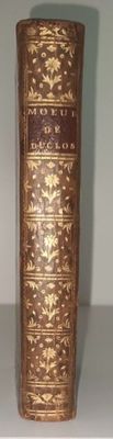 un vase doré sur une table blanche avec un ruban marron
