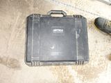 a black case sitting on the ground next to a pair of shoes