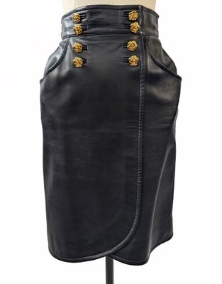 une jupe en cuir noir avec des boutons dorés sur le devant