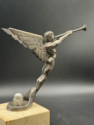 statue d'un ange tenant une trompette, posée sur un socle en marbre