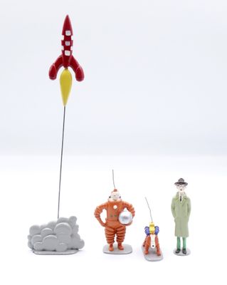 trois figurines représentant un homme et une femme debout à côté d'une fusée