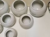 a white table with a bunch of white vases on top of it