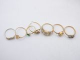 five gold rings with green stones on them on a white surface