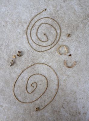 une photo d'un collier et d'une boucle d'oreille en or posés par terre