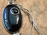 a pendant that has a black stone in it on a wooden table