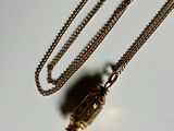a necklace that has a small gold object on it