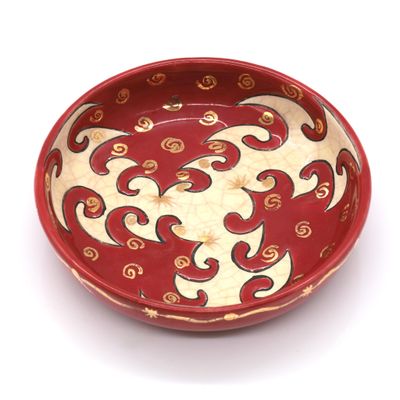 a red bowl with a design on it on a white surface