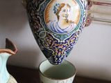 a vase with a picture of a woman on it next to a cup on a table