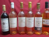six bottles of wine are lined up in a row on a red background