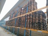 many pallets of wood stacked on a rack in a warehouse
