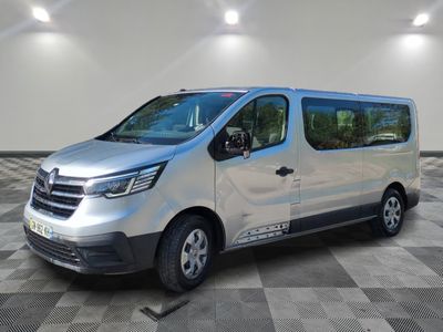 Une camionnette argentée est garée dans une pièce au sol carrelé en damier.