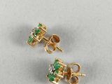 a pair of emerald and diamond earrings on a white surface